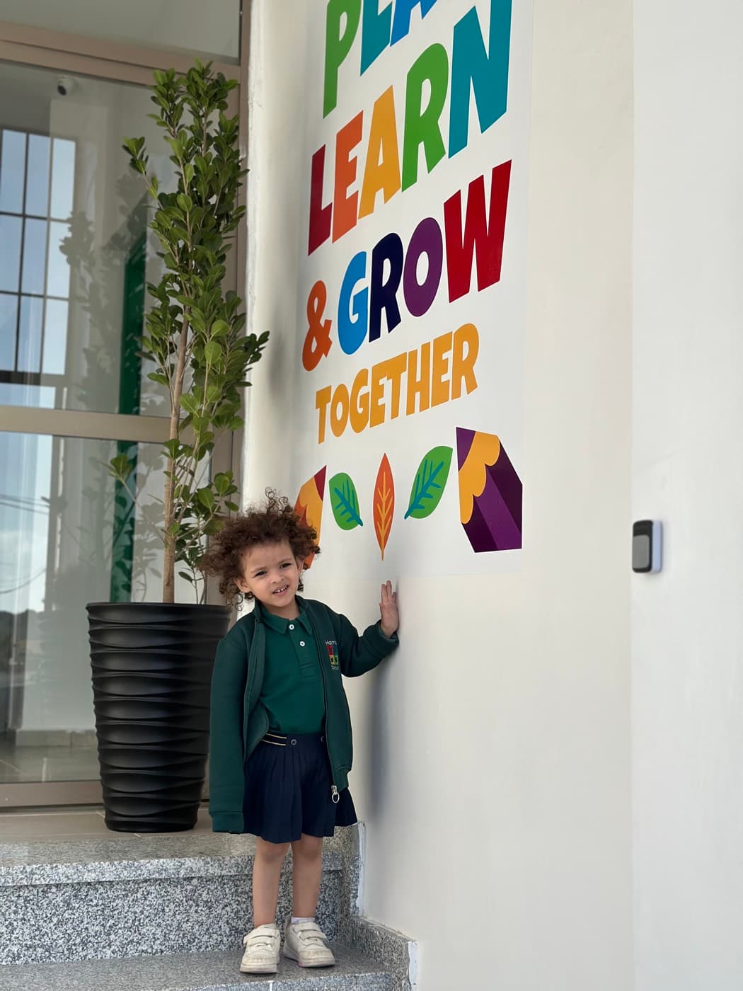 Élève devant la fresque « Play, Learn & Grow Together »